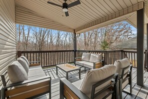 A covered outdoor deck with wooden furniture, including sofas and a coffee table. - The Witherby Woodland Retreat (Bella Vista)