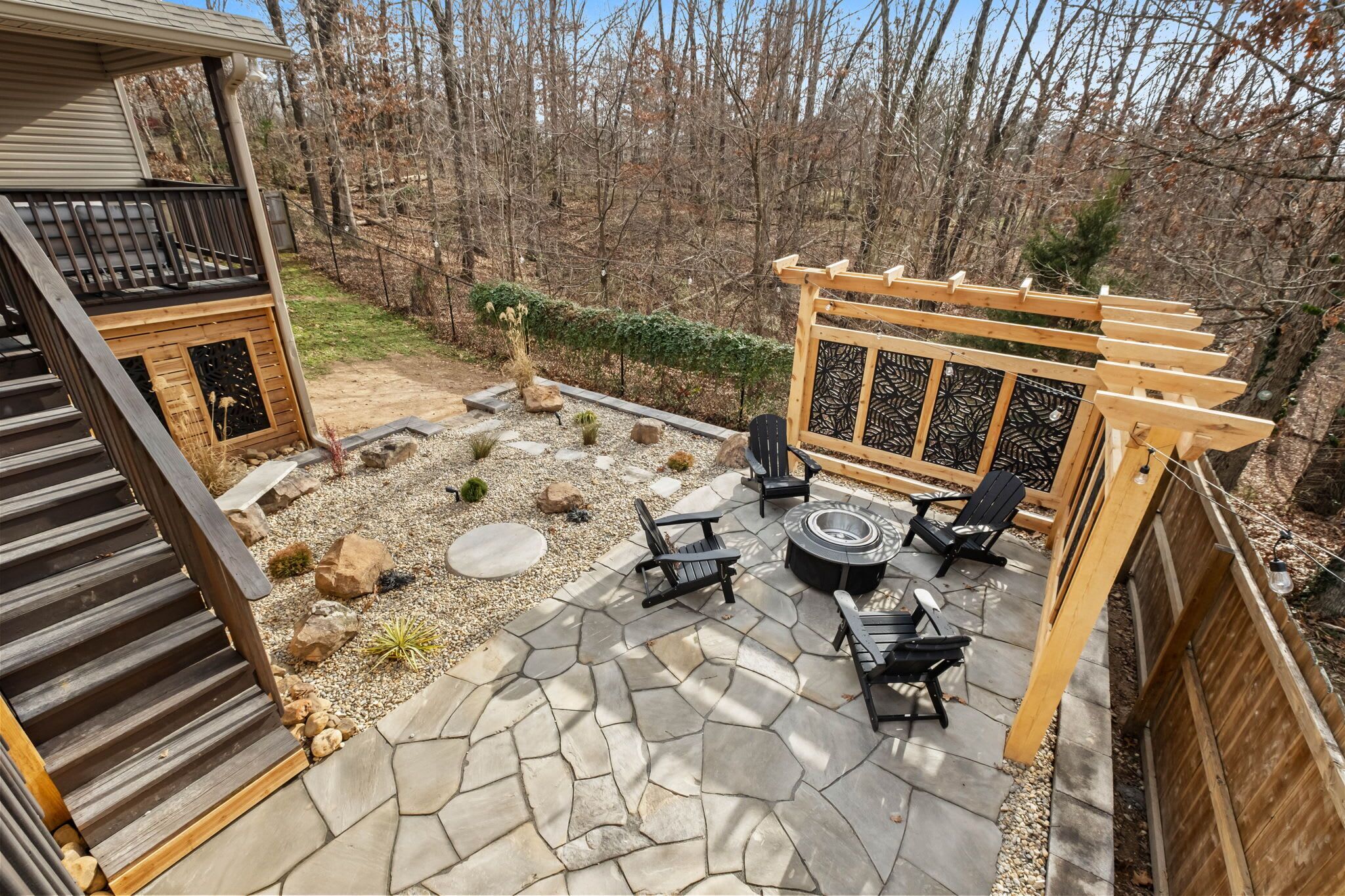 Un patio con piso de piedra, mobiliario exterior y una pérgola.
