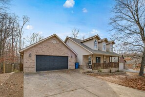 A two-story house with a garage, a covered porch, and a brick exterior. - The Witherby Woodland Retreat (Bella Vista)