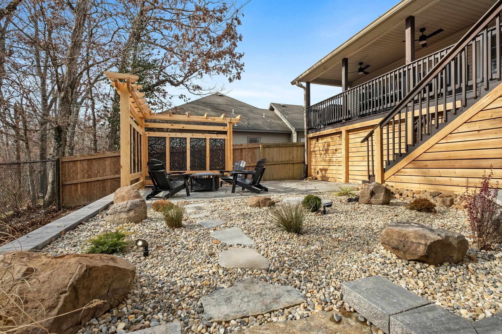 A patio with a pergola, outdoor furniture, and a stone pathway.