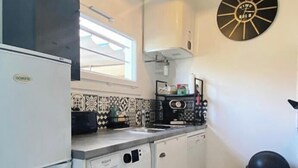 A compact kitchen with a washing machine, a refrigerator, a sink, and a clock on the wall. - L'Ecrin Marin - LA TESTE DE BUCH (LA TESTE DE BUCH)