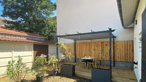 A covered patio area with a table and chairs, surrounded by potted plants and a wooden fence. - L'Ecrin Marin - LA TESTE DE BUCH (LA TESTE DE BUCH)
