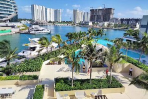 Un resort con piscina, palmeras y un puerto deportivo con barcos.