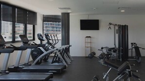 Une salle de sport équipée de tapis de course, de vélos elliptiques et de matériel de musculation.