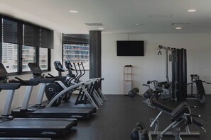 Un gimnasio con cintas de correr, elípticas y equipo de pesas.