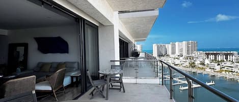 A balcony with a glass railing overlooking a marina and cityscape.