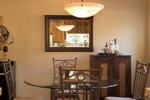 A dining area with a round glass table, metal chairs, a wooden cabinet with bottles, and a mirror on the wall. - Ultimate Mountain Retreat! (South Lake Tahoe)