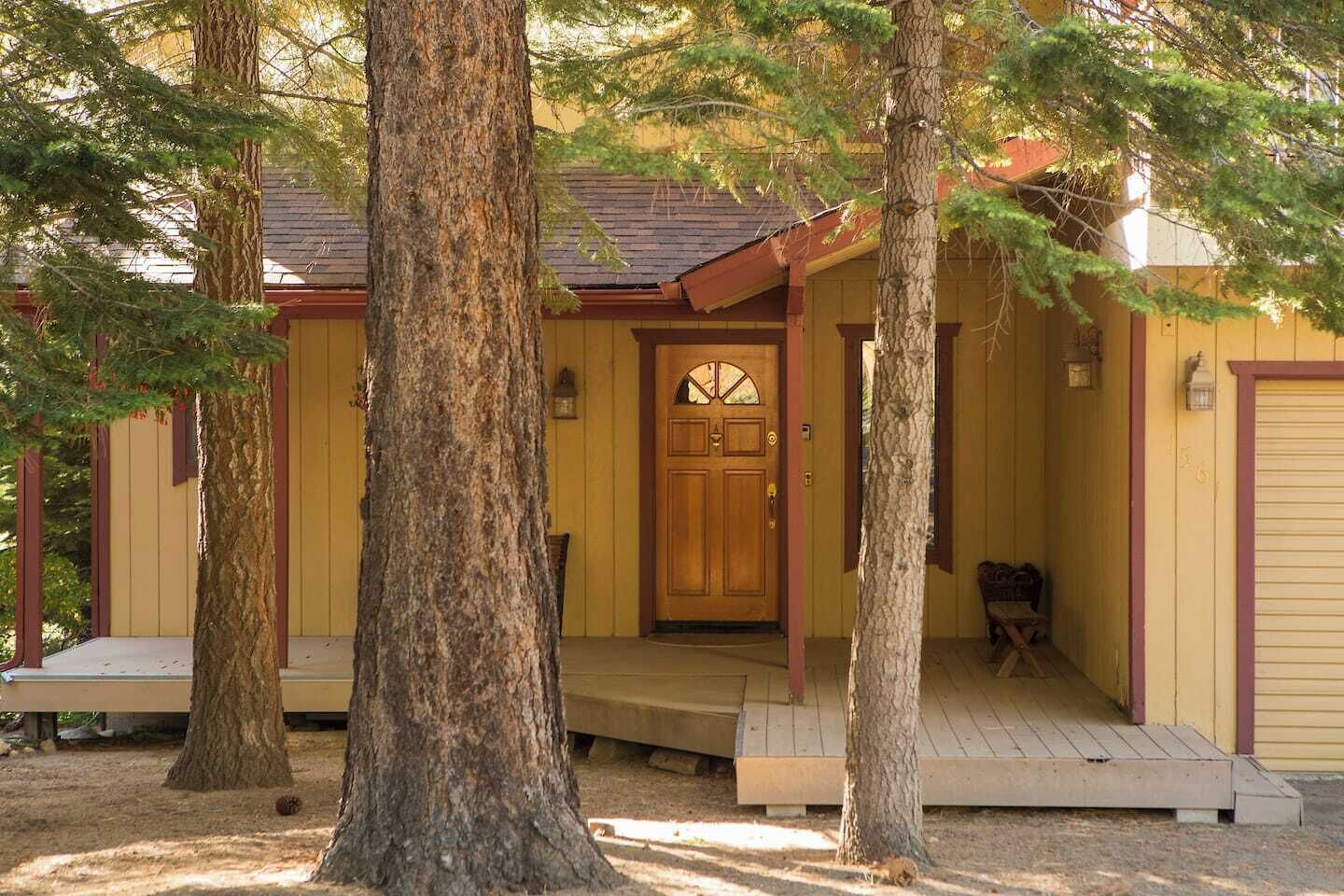 Eine Holzhütte mit Veranda, einer Tür mit Fenster und einer Bank.