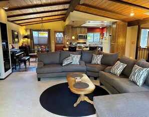 Ein Wohnzimmer mit einem Ecksofa, einem Couchtisch und einem Klavier.