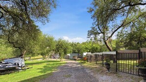 A gravel path leading to a gated area with RVs parked on the left. - Lake Travis Lakefront Cabin with Cowboy Pool (Leander)