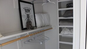 A white closet with a hanging rack, shelves, and a framed picture. - Lake Travis Lakefront Cabin with Cowboy Pool (Leander)