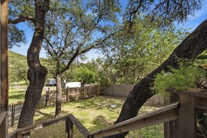 Un patio trasero cercado con árboles, una terraza de madera y un tanque de almacenamiento blanco.