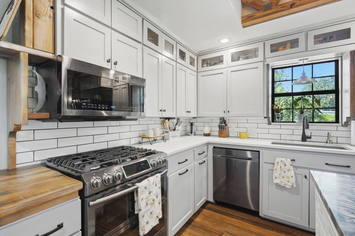 A modern kitchen with white cabinetry, a stainless steel stove, and a dishwasher.