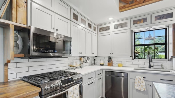 A modern kitchen with white cabinetry, a stainless steel stove, and a dishwasher.