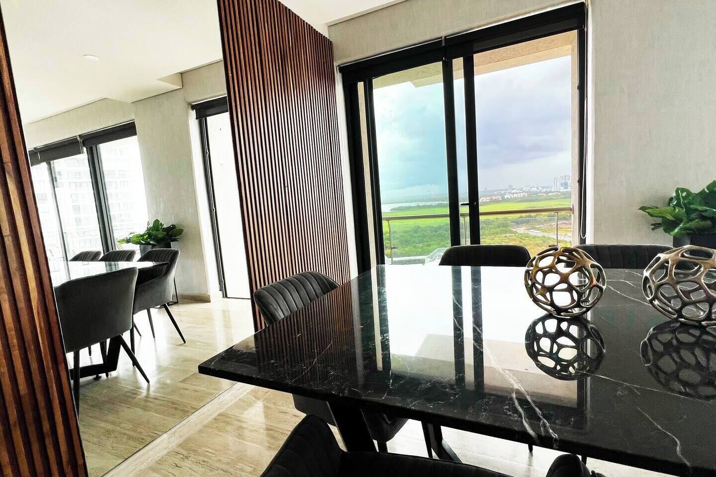 Un espace repas moderne avec une table en marbre noir, deux chaises et des vases décoratifs.