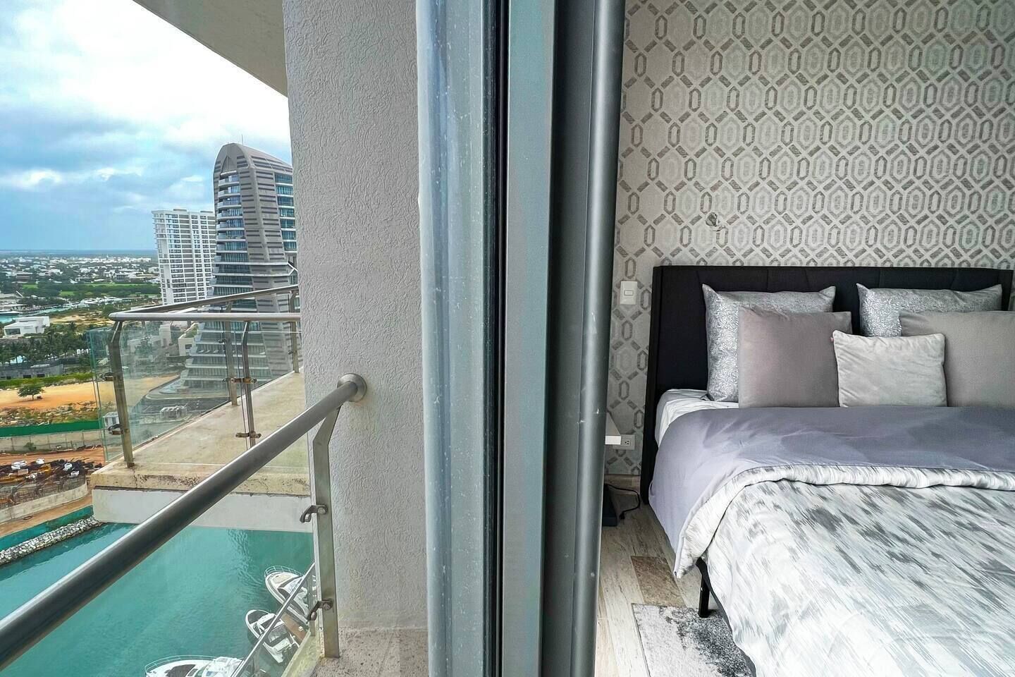 Ein Balkon mit Pool, ein Bett mit Kissen und einer Wand mit Muster.