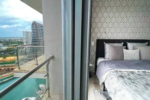 Ein Balkon mit Pool, ein Bett mit Kissen und einer Wand mit Muster.