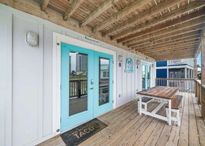 A covered wooden deck with a bench, a turquoise door, and a doormat with 'YOU'RE THE BEST TACO' text. - Pipedreams West (Gulf Shores)