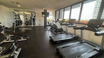 A gym with treadmills, weight machines, and a cross in the center.