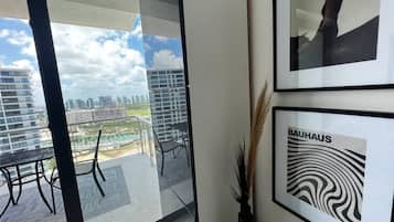 Ein modernes Interieur mit Balkon, gerahmten Kunstwerken und Blick auf eine Stadtlandschaft.