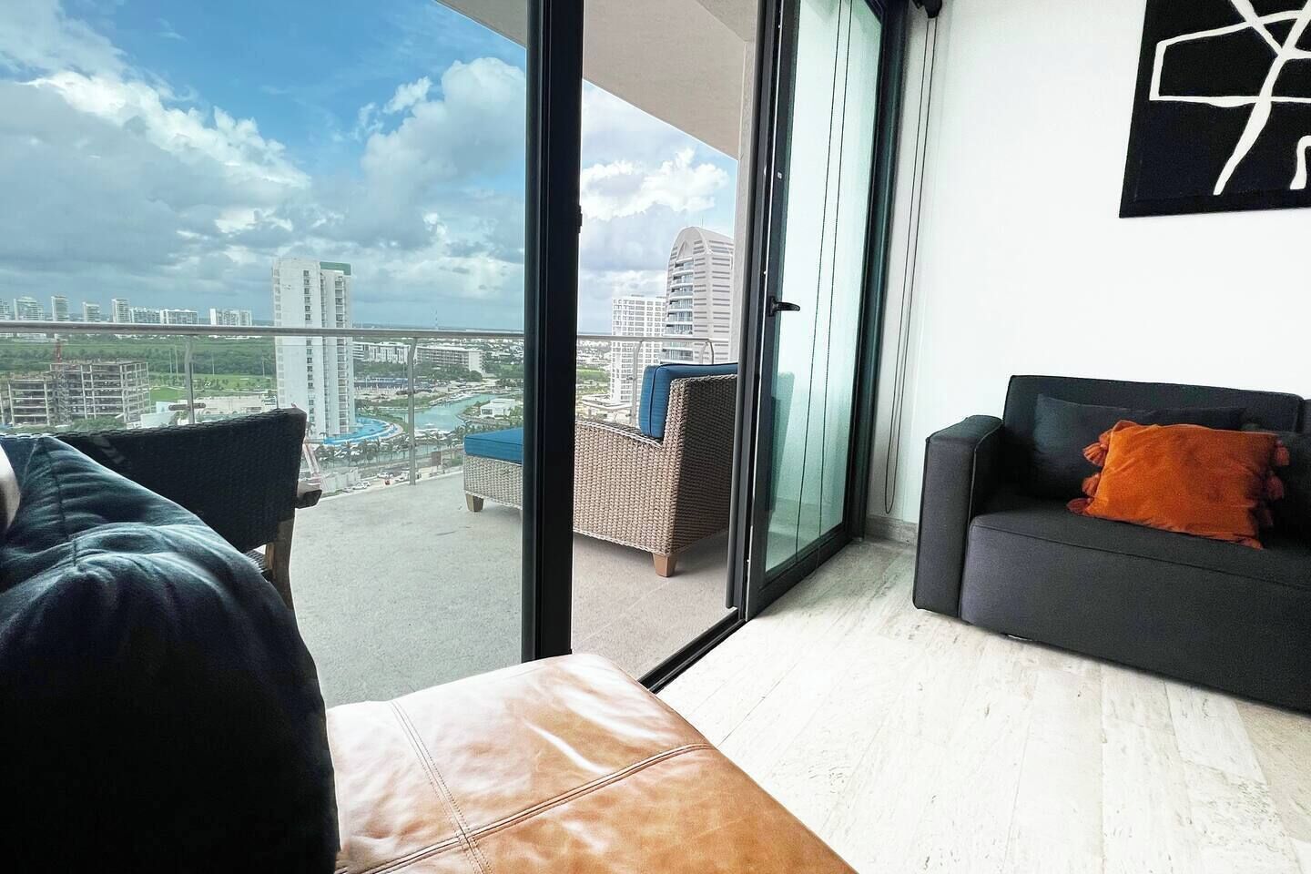 Una sala de estar moderna con balcón, un sofá, una butaca y vistas de la ciudad.