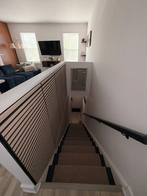 Eine Treppe mit Handlauf, einem Heizkörper und einem an der Wand montierten Fernseher.