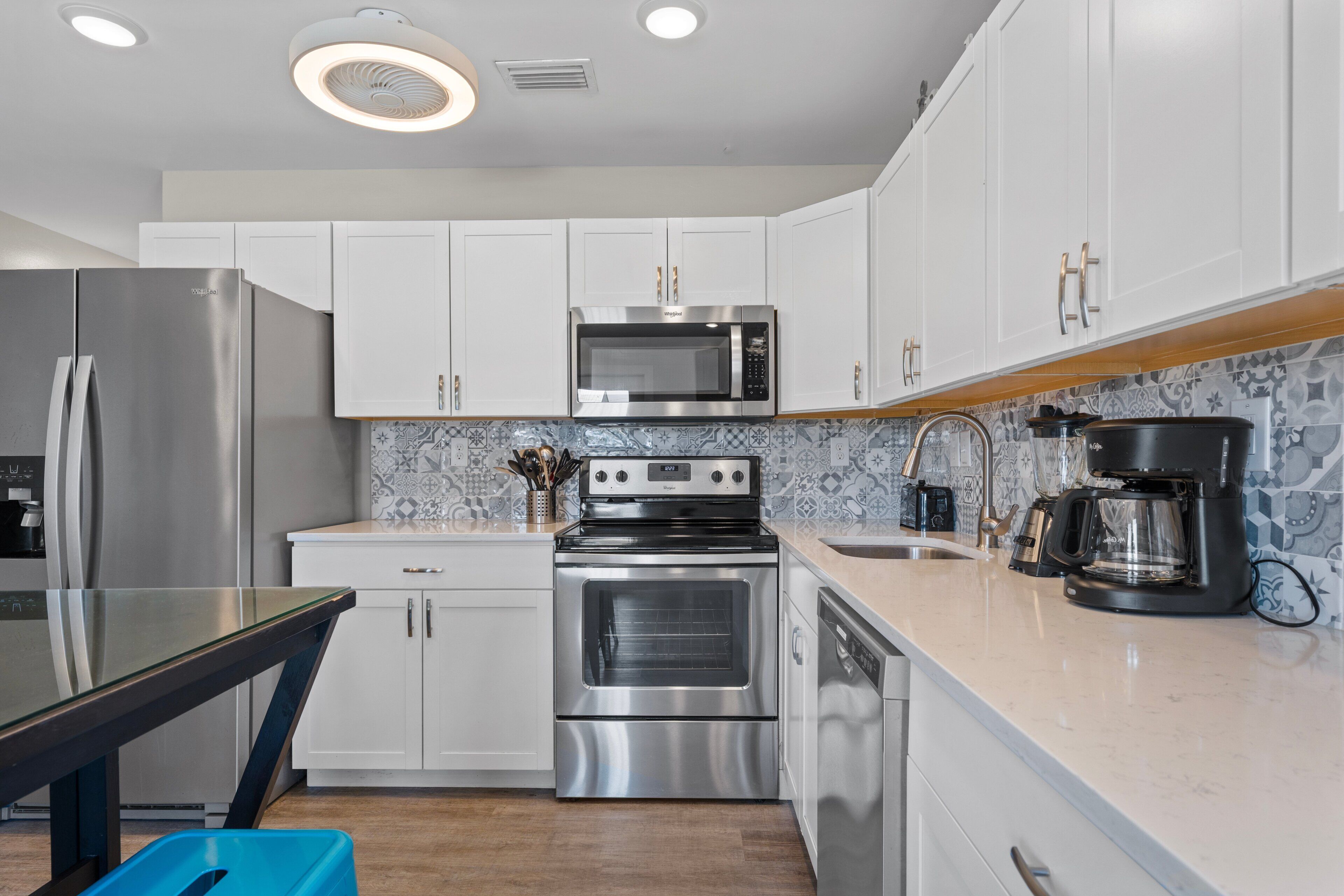 Una cocina moderna con electrodomésticos de acero inoxidable, armarios blancos y un salpicadero con diseño.