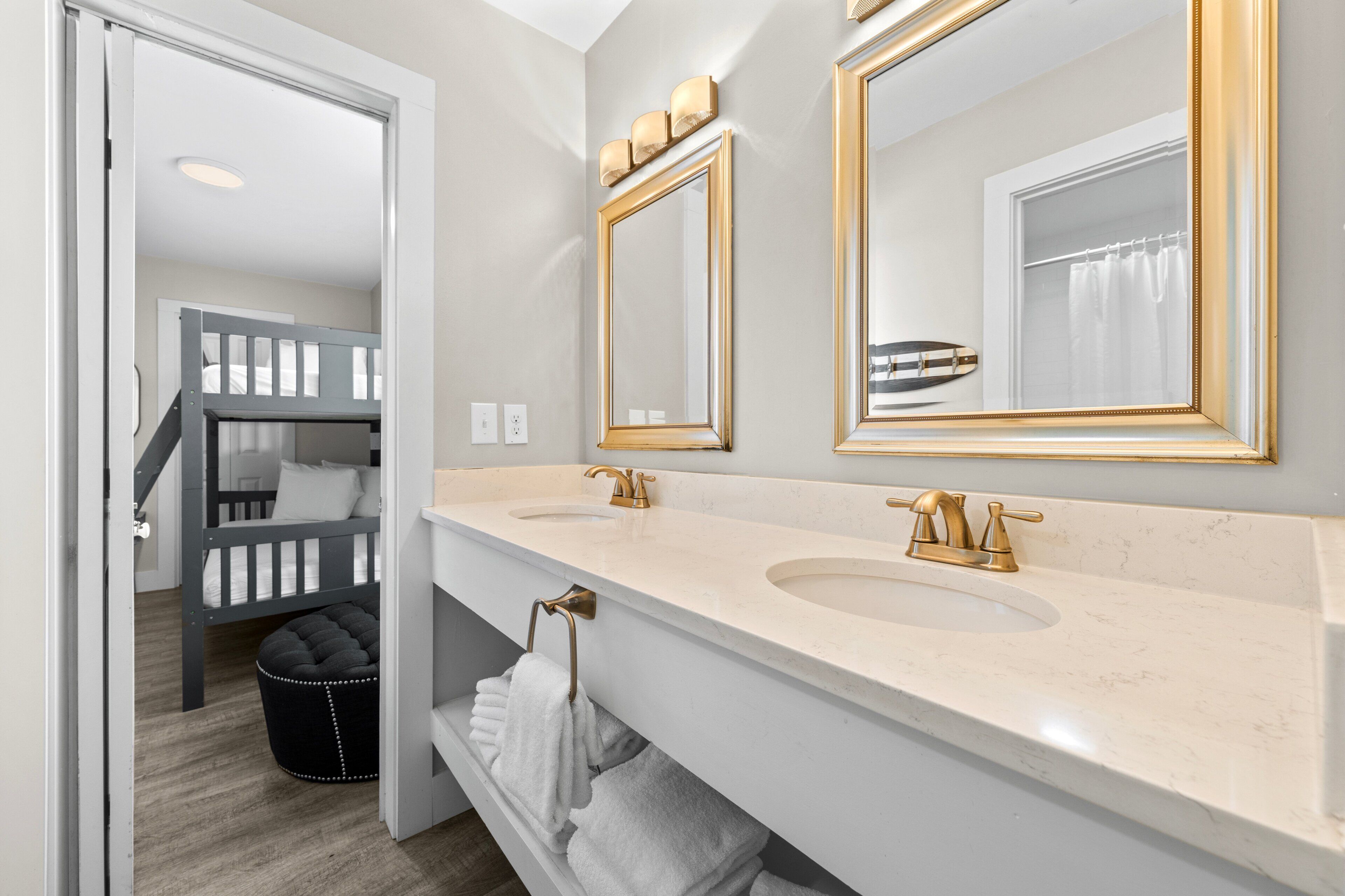 A bathroom with two sinks, gold faucets, and a large mirror with a gold frame.