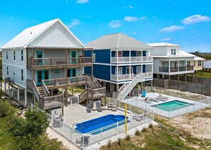 A beachfront property with multiple buildings, a swimming pool, and a fenced deck area. - Pipedreams East (Gulf Shores)