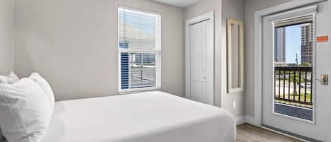 A bedroom with a bed, a ceiling fan, a door, and a window.