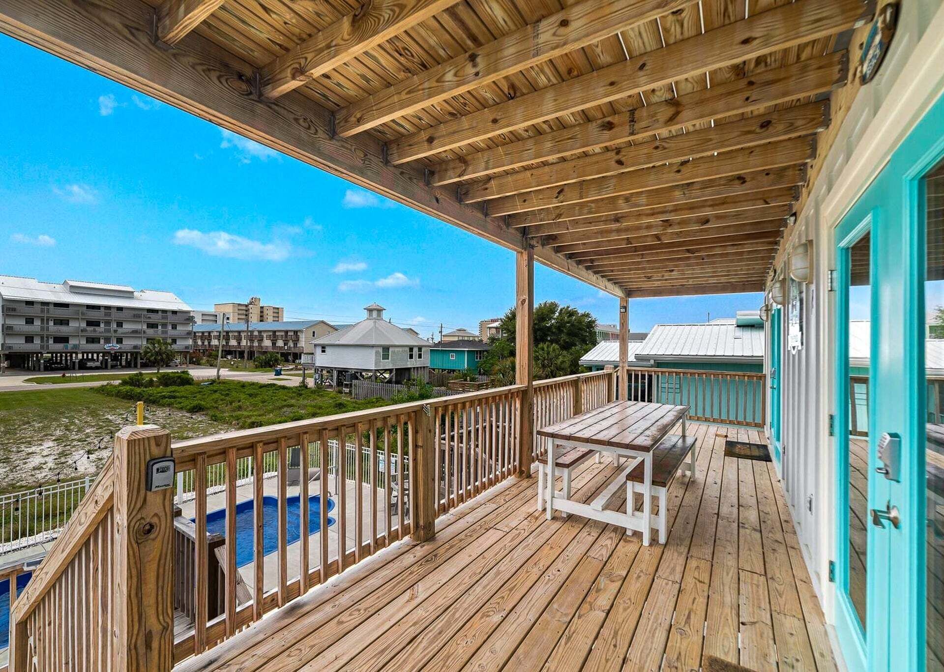 Una terraza de madera con piscina, una mesa y vistas a otros edificios.