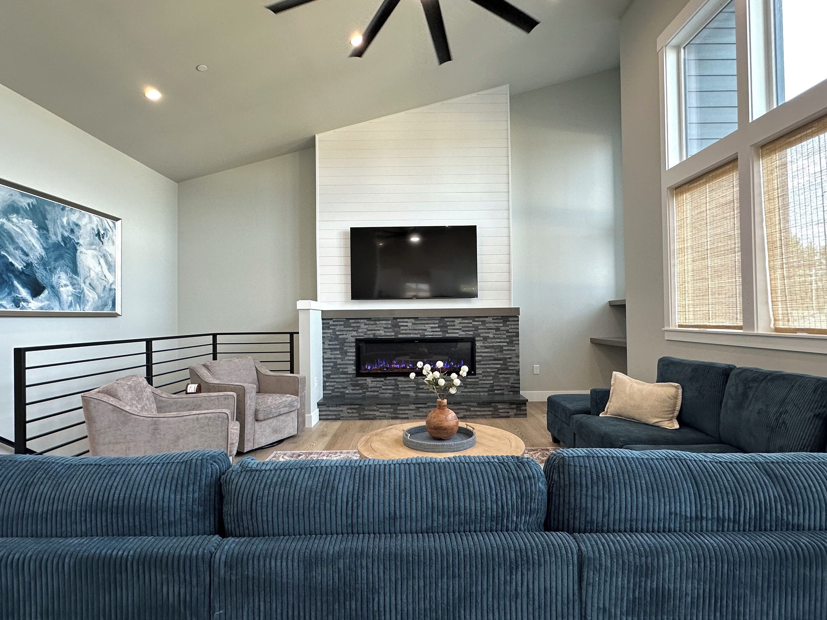 A modern living room with a fireplace, a flat-screen TV, and a large window.