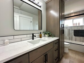 A modern bathroom with a large mirror, a sink, and a toilet. - Hot Tub+Speakeasy · Sleeps 9 · Walk Downtown/Beach (Ocean Shores)