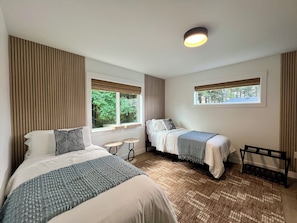 A bedroom with two beds, a window, a small table, and a bench. - New Speakeasy · Sleeps 9 · Walk Downtown/Beach (Ocean Shores)
