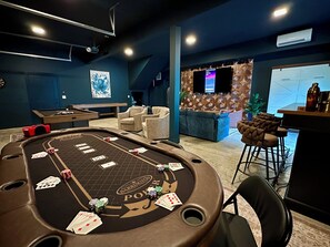 Een casinoroom met een pokertafel, stoelen, een pooltafel en een bar.