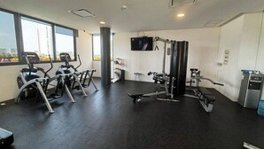 A gym with cardio machines, weightlifting equipment, and a TV screen. - TOP/1BR/Contemporary Condo/Huge Terrace/Gym/HZ (Cancún)