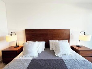 Habitación de hotel con una cama grande, dos mesitas de noche con lámparas y un cabecero de madera.