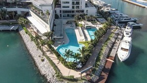 A resort with a central swimming pool, adjacent to a marina with yachts. - TOP/1BR/Contemporary Condo/Huge Terrace/Gym/HZ (Cancún)