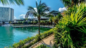 Ein Hotel am Wasserufer mit Pool, Palmen und Blick auf die Skyline der Stadt.