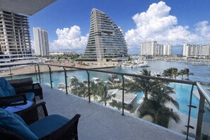 Un balcon offrant une vue sur un port de plaisance, des yachts et des immeubles modernes de grande hauteur.