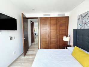 A hotel room with a bed, a TV mounted on the wall, a wardrobe, and a painting on the wall. - TOP · Puerto Cancún · Café y balcón frente a yates (Cancún)