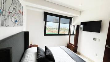 Une chambre à coucher comprenant un lit, une fenêtre, un téléviseur à écran plat et une œuvre d’art accrochée au mur.
