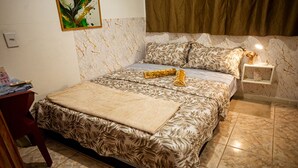 Quarto com cama, mesa de cabeceira, prateleira na parede e uma pintura.
