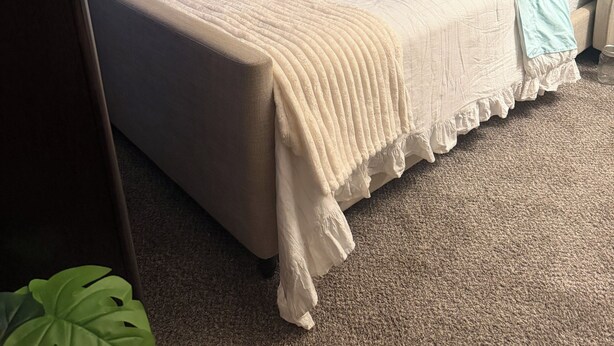 Un dormitorio con cama, una silla, una mesita de noche y un cuadro colgado en la pared.
