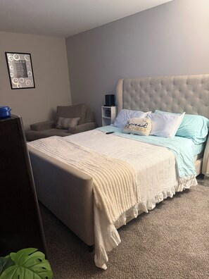 A bedroom with a bed, a chair, a bedside table, and a wall-mounted picture. - 2-bedroom 2 bath apartment in pleasant Indianapolis with cool AC (Indianapolis)
