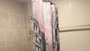 Un baño con cortina de ducha con diseño de paisaje urbano, un inodoro y una bañera.