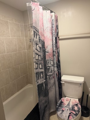 A bathroom with a shower curtain featuring a cityscape design, a toilet, and a bathtub. - 2-bedroom 2 bath apartment in pleasant Indianapolis with cool AC (Indianapolis)