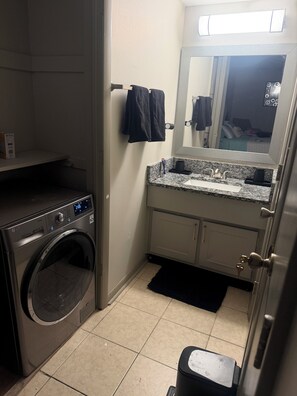 A compact laundry room with a washing machine, a sink with a mirror, and a small cabinet. - 2-bedroom 2 bath apartment in pleasant Indianapolis with cool AC (Indianapolis)