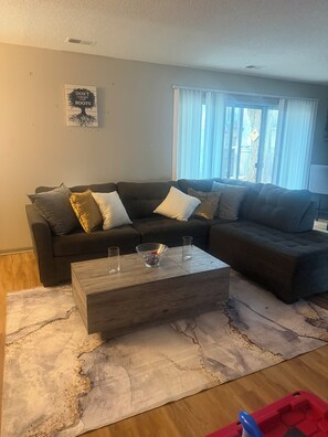 A living room with a sectional sofa, a coffee table, and a rug. - 2-bedroom 2 bath apartment in pleasant Indianapolis with cool AC (Indianapolis)
