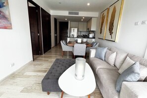 Un salon moderne comprenant un canapé, une table basse et un coin repas avec des chaises.